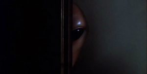 An alien pokes head from behind a door.